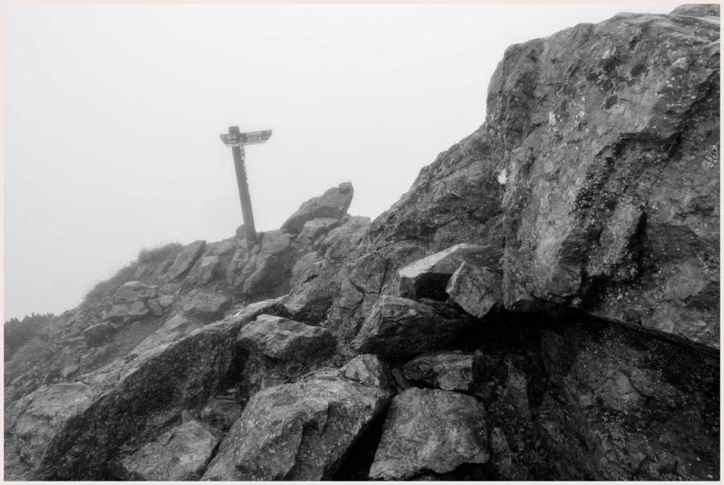 Cloudy views of nothing but rocks and the summit marker at the Mt. Shiomi summit.